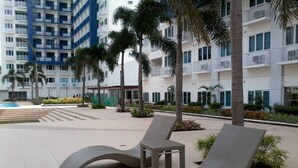 A modern outdoor lounge area with curved lounge chairs and a pool in the background.