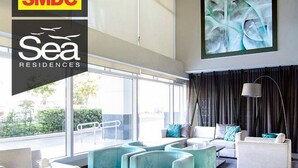 A modern living room with a large window, a sofa, a coffee table, and a lamp.