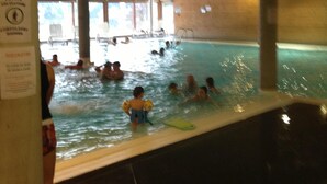 Una piscina interior amb persones nedant i de peu a l'aigua.