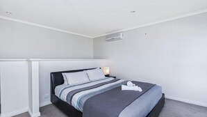 A modern bedroom with a bed, white walls, and a ceiling vent. - Bella On Victoria - with ocean views (Port Fairy)