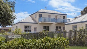 A two-story building with a balcony on the second floor, a sign reading "OCEAN VIEW", and a wooden fence in the foreground. - Bella On Victoria - with ocean views (Port Fairy)