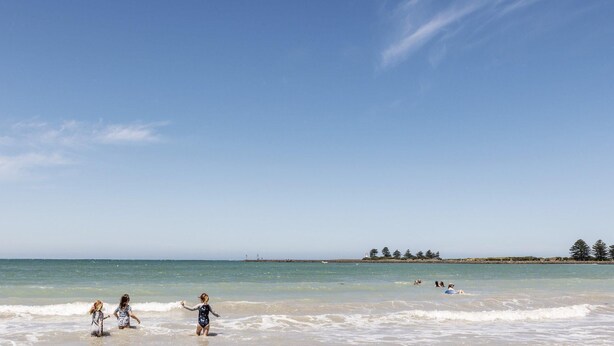 A beach with clear skies, calm waters, and a distant shoreline with trees. - Bella On Victoria - with ocean views (Port Fairy)