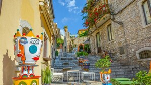 Una calle estrecha con esculturas coloridas y fantásticas, y edificios de piedra.