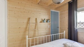 A wooden-paneled room with a bed, a ladder, and a door. - Moyo Kijani Cosy Lodge (Zandvoort)