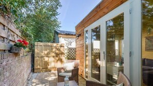 A patio with wicker furniture, a brick wall, and a wooden fence. - Moyo Kijani Cosy Lodge (Zandvoort)
