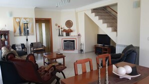 A living room with a fireplace, a television, and a staircase.