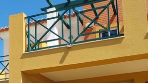 A two-story building with a balcony, a front door, and a potted plant.