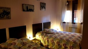 Een slaapkamer met twee bedden, een hoofdbord, een raam met gordijnen en wanddecoratie.