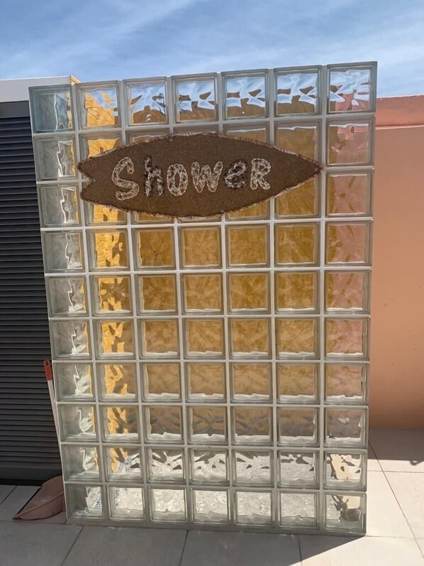 Un’area doccia con un divisorio in vetro e un cartello con scritto 'Shower'.
