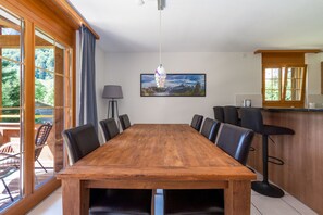 A conference room with a wooden table, black chairs, a large window, and a painting on the wall. - Apartment Arven - 3 Bedroom - 2 Bathroom - Uninterrupted mountain view (Lauterbrunnen)
