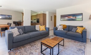 A modern living room with two grey sofas, a wooden coffee table, and a patterned rug. - Apartment Arven - 3 Bedroom - 2 Bathroom - Uninterrupted mountain view (Lauterbrunnen)