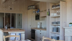 Een houten interieur met een keukenhoek, eettafel, stoelen en een aanrecht.
