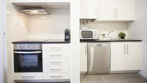 A modern kitchen with white cabinets, a built-in oven, a microwave, and a dishwasher. - Lisbon Amazing Castel View (Lisboa)