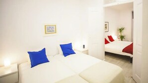 A hotel room with a white bed, two blue pillows, a small bedside table with a lamp, and a framed picture on the wall. - Lisbon Amazing Castel View (Lisboa)