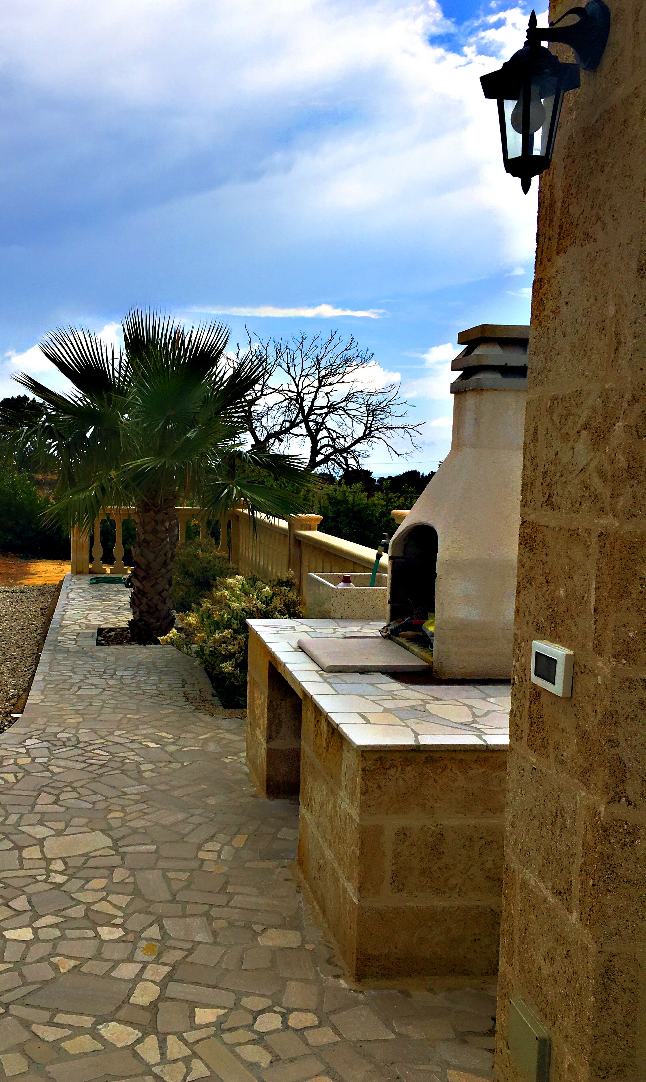 A stone pathway leading to a building with a stone wall and a lantern.