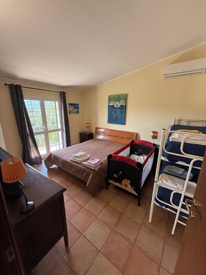 A room with a bed, a desk, a chair, a window with curtains, a painting, and a bunk bed.