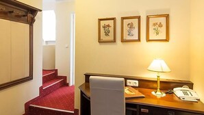 A hotel room with a desk, a telephone, a lamp, and a staircase. - Klassik Hotel Am Tor (Weiden in der Oberpfalz)