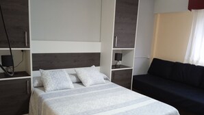 Ein modernes Schlafzimmer mit einem Bett, einer dunklen Couch und integrierten Regalen.