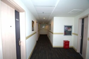 A hotel corridor with doors, framed pictures, and a red box on the floor. - Jinjiang Inn (Baoding Junxiao Square) (Baoding)