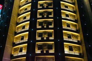 A multi-story hotel with balconies and illuminated windows.