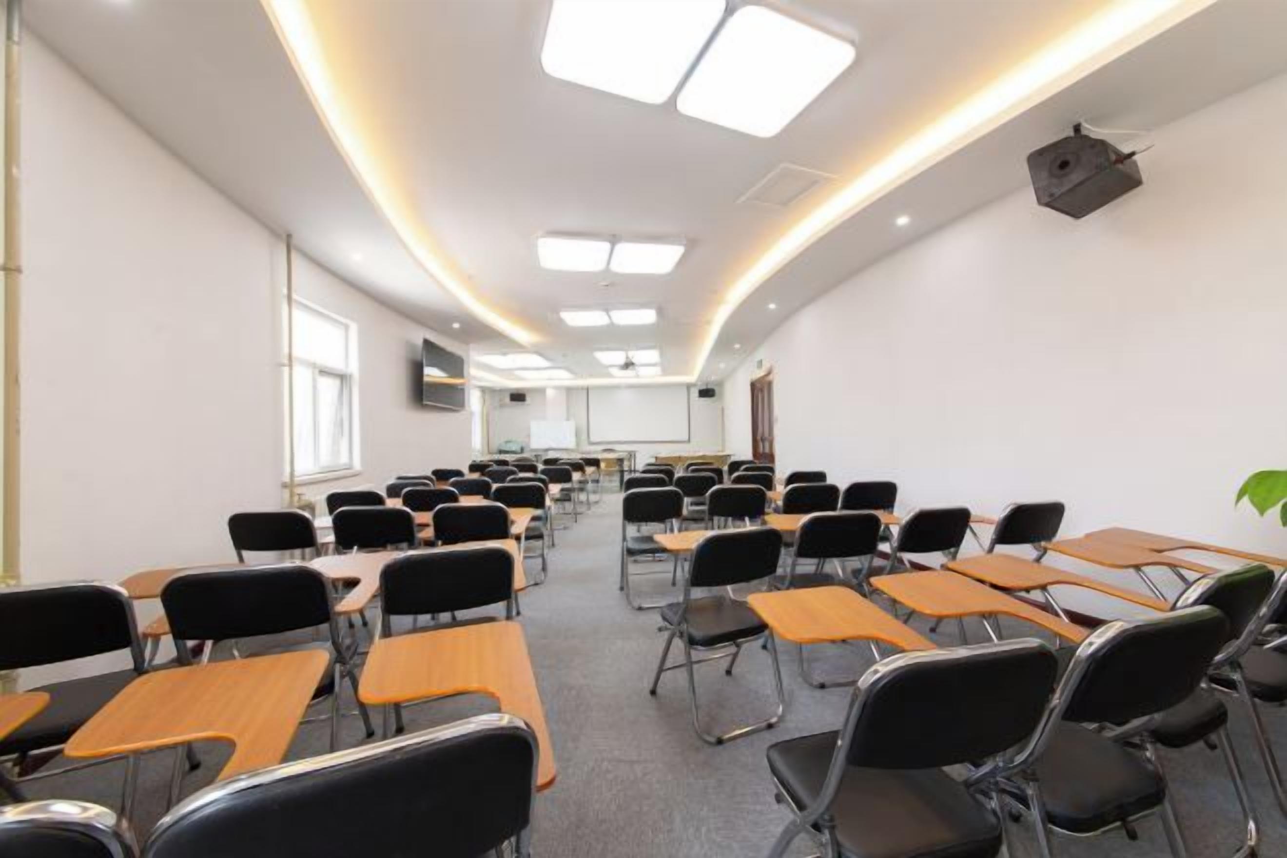 A classroom with rows of desks and chairs, a projector, and a screen.