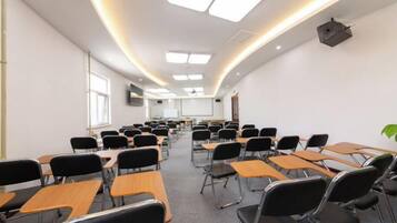 A classroom with rows of desks and chairs, a projector, and a screen.