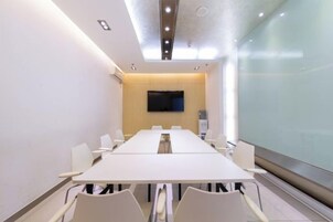 Une salle de conférence équipée d’une longue table, de chaises, d’un téléviseur à écran plat et d’une cloison en verre.