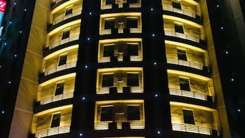A multi-story building with balconies and illuminated windows.