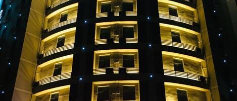 A multi-story building with balconies and illuminated windows.