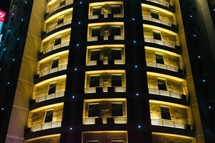 A multi-story building with balconies and illuminated windows.