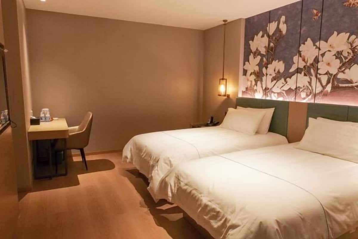 A hotel room with two beds, a desk, and a chair.