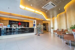 A hotel lobby with a reception desk, seating area, and a modern design.