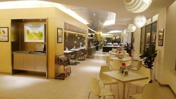 A hotel lobby with a reception desk, seating area, and a staircase leading to upper floors.
