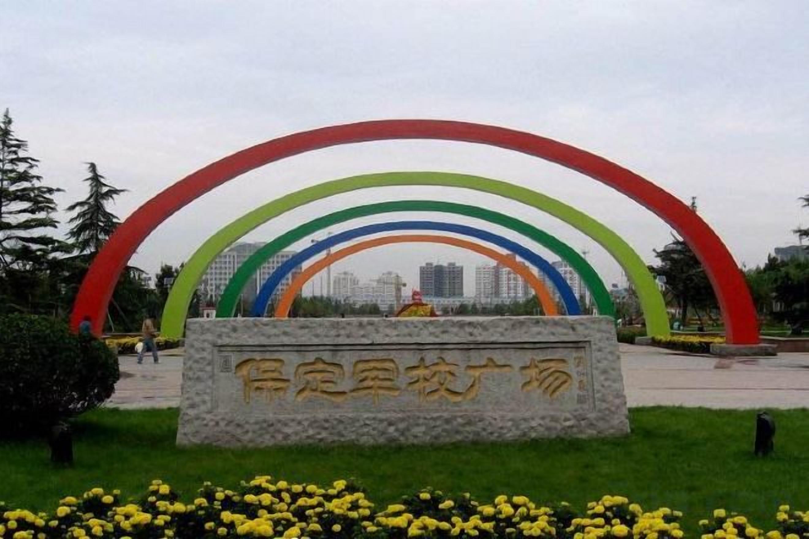 A park with a stone monument and a colorful arch structure.