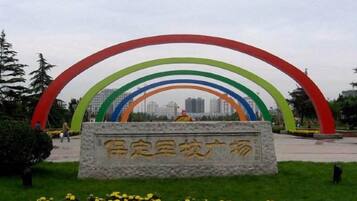 A park with a stone monument and a colorful arch structure.