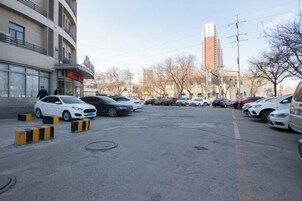 A parking lot with multiple cars, a building with a sign, and a tall building in the background.