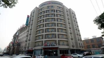 A multi-story hotel with a curved facade, multiple balconies, and a prominent entrance.