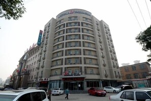 A multi-story hotel with a curved facade, multiple balconies, and a prominent entrance.