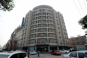 Un hôtel à plusieurs étages, doté d’une façade incurvée, de nombreux balcons et d’une entrée imposante.