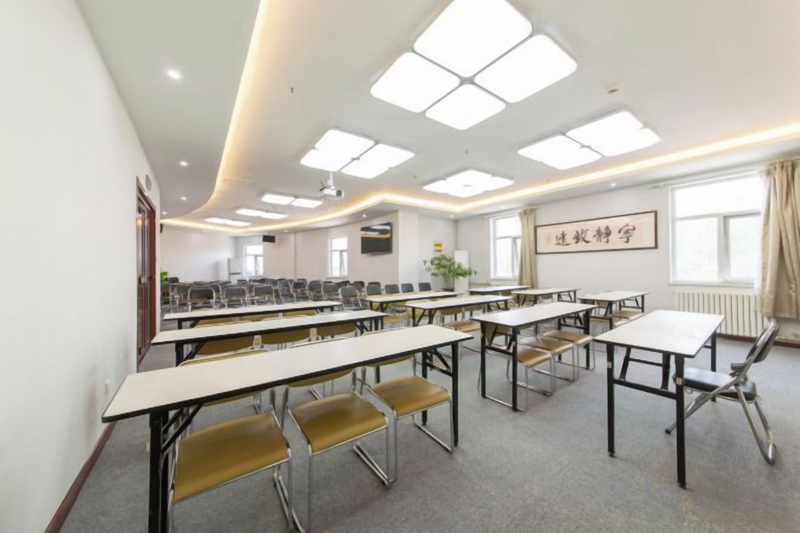 A conference room with multiple tables and chairs, a projector, and a large window with curtains.