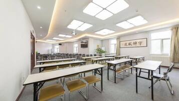 A conference room with multiple tables and chairs, a projector, and a large window with curtains.