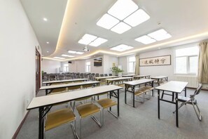 A conference room with multiple tables and chairs, a projector, and a large window with curtains.