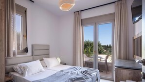 Een moderne hotelkamer met een groot bed, een bureau en een balkon met buitenmeubilair.