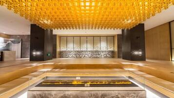 Un hall d’entrée spacieux avec un comptoir de réception en marbre, un grand espace salon et un plafond décoratif.
