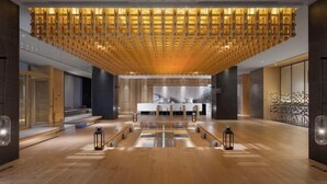 A modern lobby with a wooden ceiling design, a central reception desk, and a reflective floor. - Zhuozheng International Hotel (Baoding)