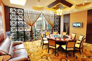A hotel room with a dining area, a sofa, and a TV mounted on the wall. - Zhuozheng International Hotel (Baoding)