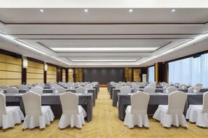 A conference room with rows of tables and chairs, a stage, and a large screen. - Zhuozheng International Hotel (Baoding)