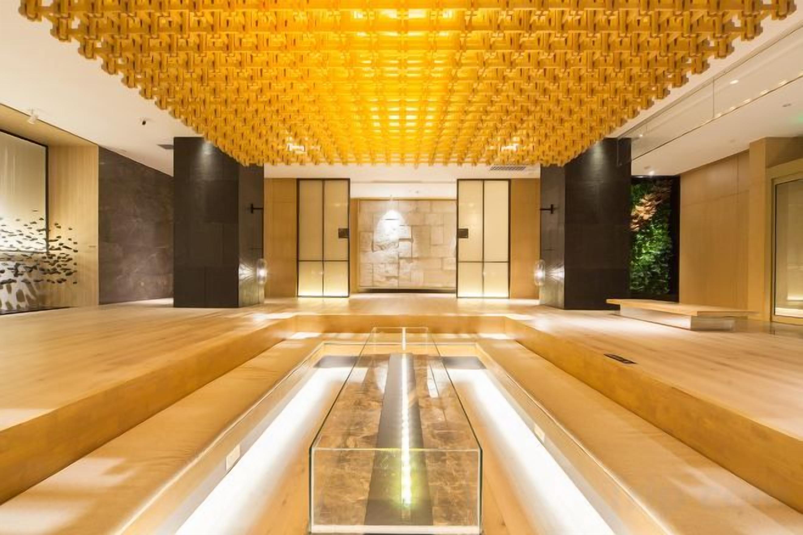 Un hall d’entrée spacieux doté d’un sol central réfléchissant, d’un plafond orné de motifs et d’un design moderne.