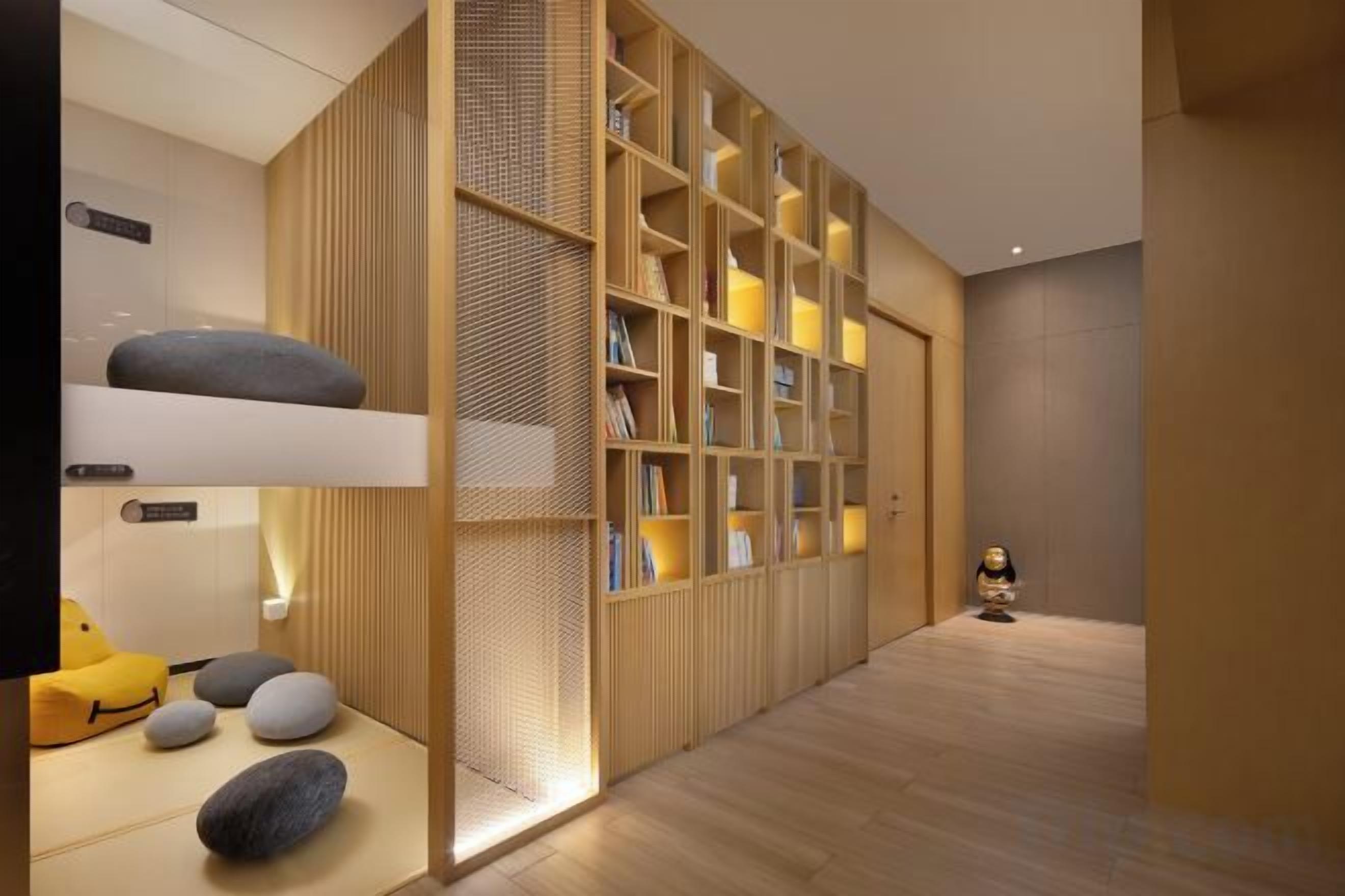 A modern interior with a wooden bookshelf, a bunk bed, and a small statue.