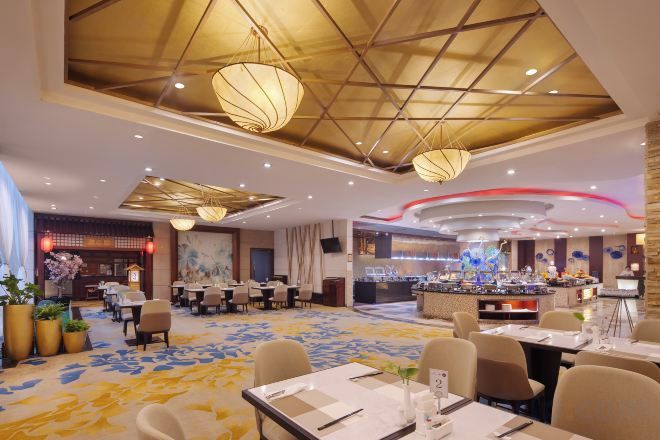 A hotel dining area with tables, chairs, and a buffet.